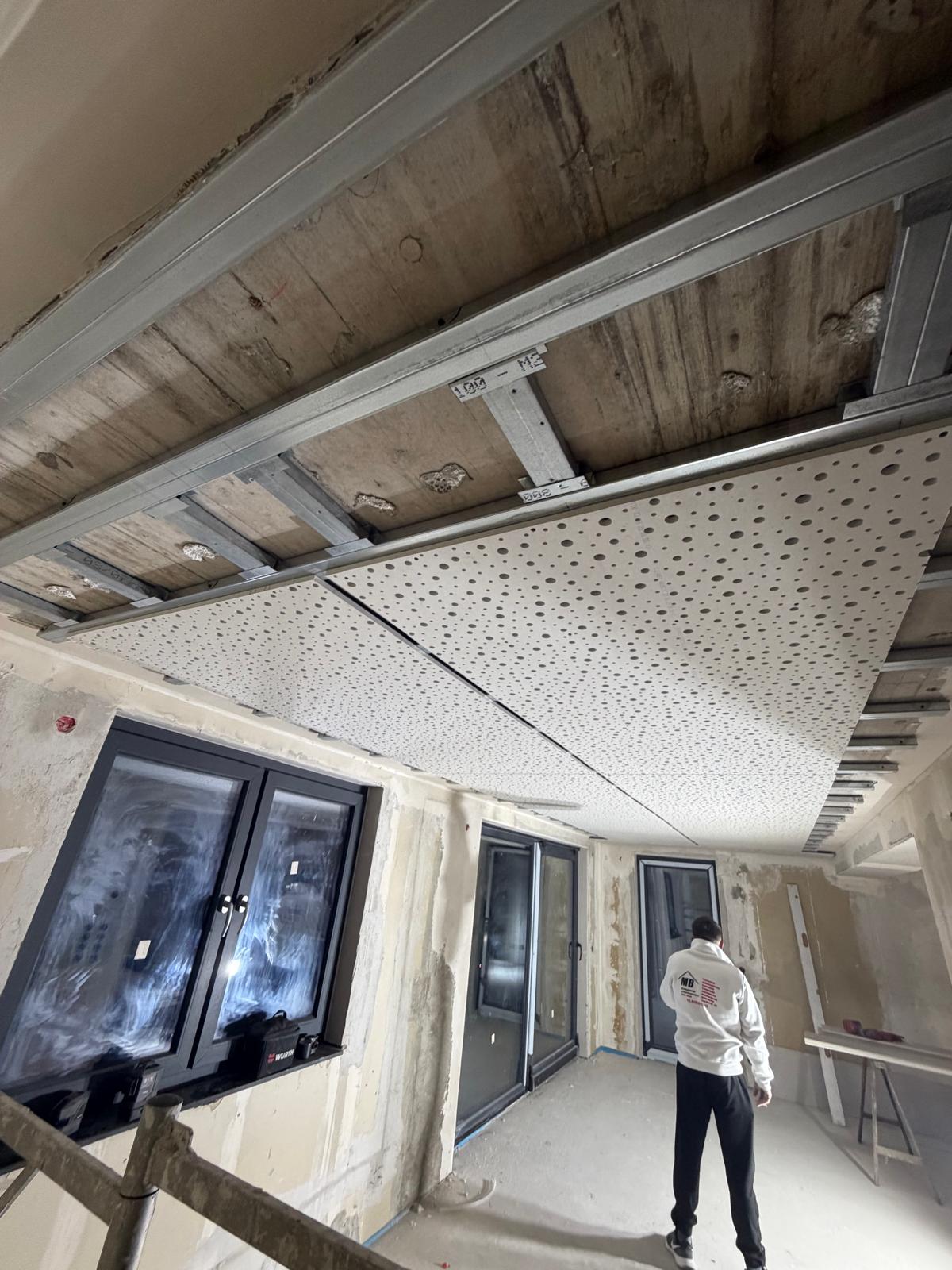 MB-Mitarbeiter montiert eine Akustikdecke auf der Baustelle