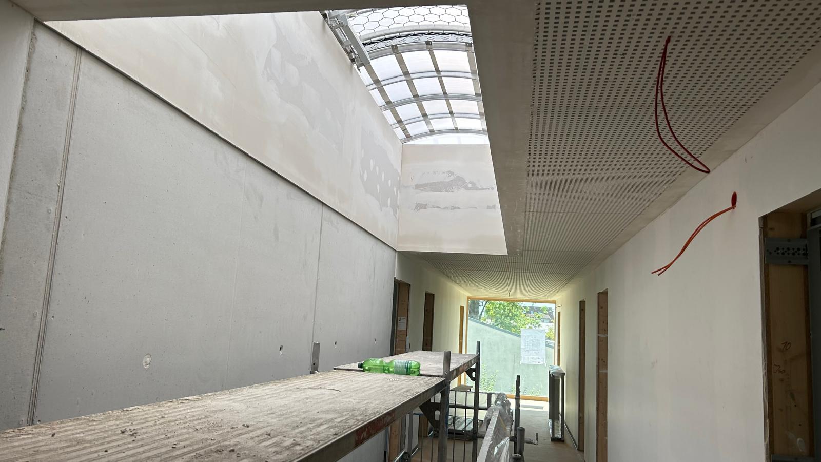 Flur mit Glasdach-Lichthof im Rohbau eines Gewerbebaus